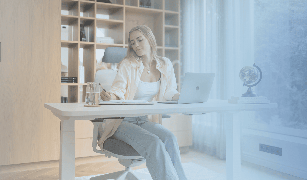 young woman sitting in a home office working behind an ergonomic standing desk