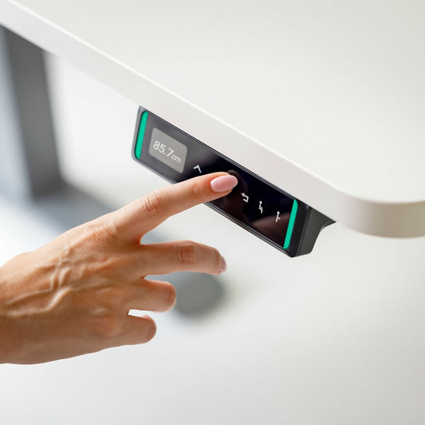 Hand interacting with a digital control panel on a stand-up desk