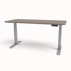 An adjustable height standing desk with a light brown wood-grain top and gray metal legs, shown on a clean white background.