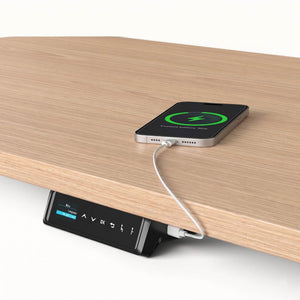 Smartphone charging on a wooden surface with a control panel underneath.